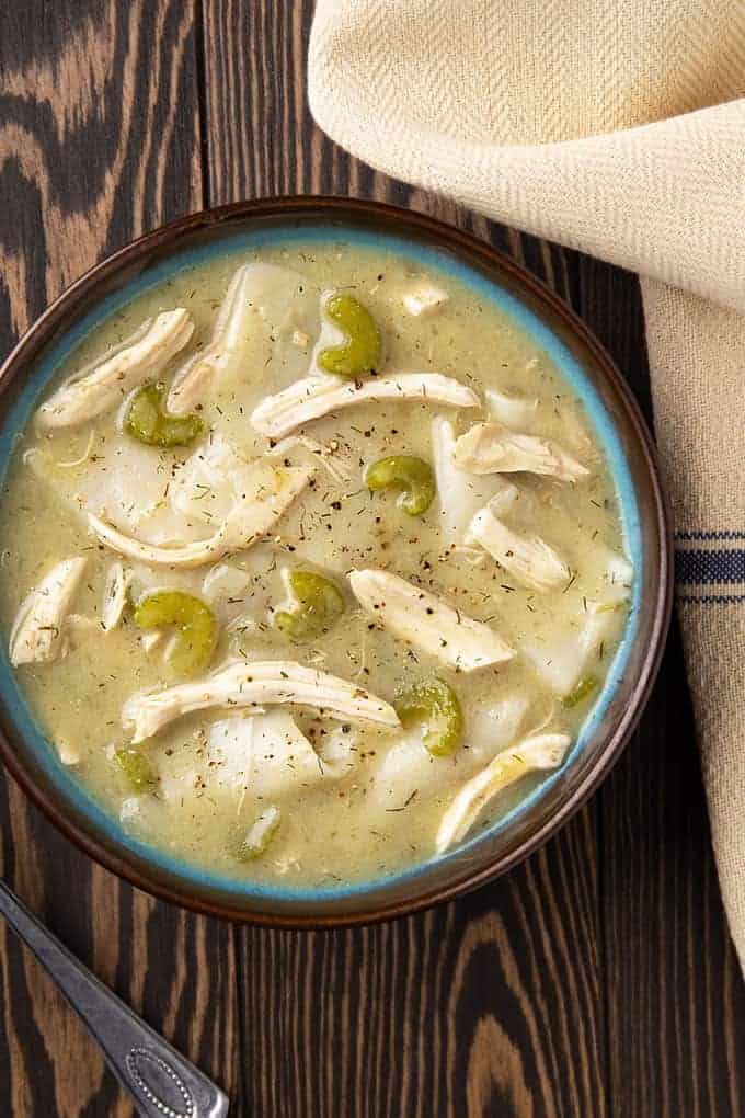 Chicken and Dumplings in a blue and brown bowl on a wooden background.