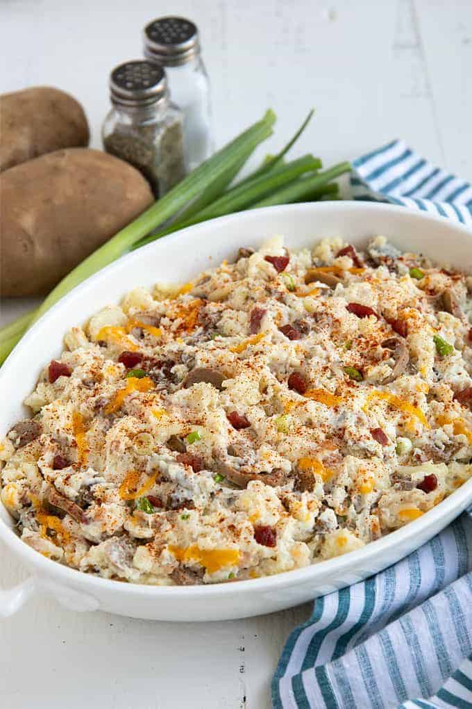 Loaded baked potato casserole in an oval white baking dish.