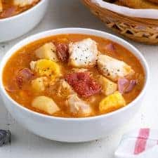 Front view of stew in a white bowl on a white surface.