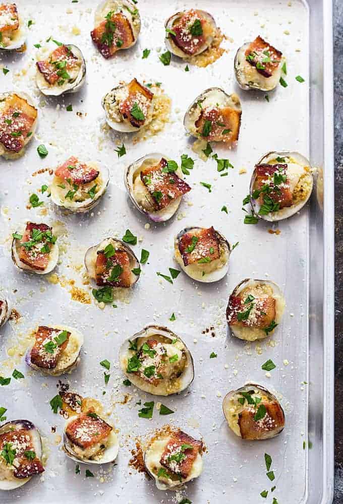 Overhead view of clams casino topped with fresh chopped parsley on a baking sheet.