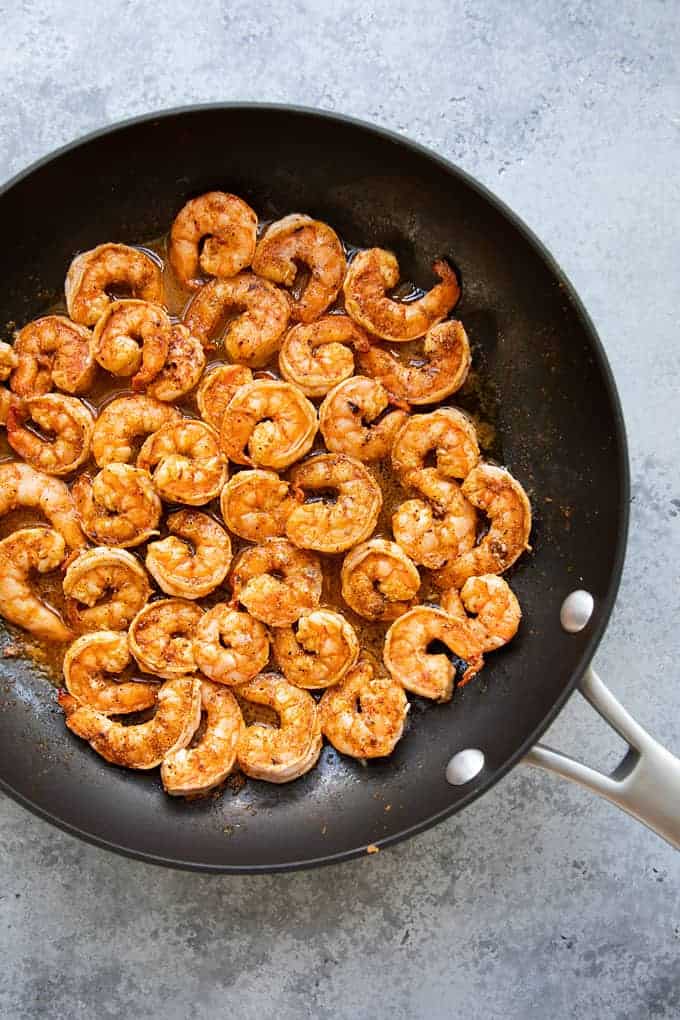 Overhead view of cooked taco-seasoned shrimp in a large skillet.