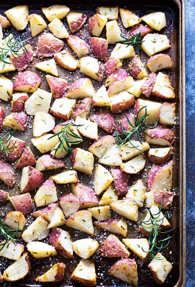 Overhead view of roasted red potatoes with rosemary and Parmesan on a baking sheet.