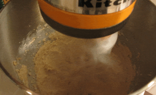 Closeup of an orange stand mixer beating cookie batter.