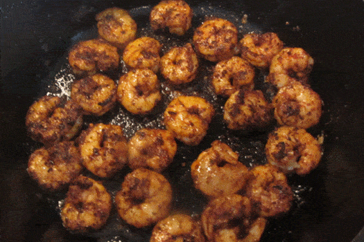Closeup of blackened shrimp in a skillet.