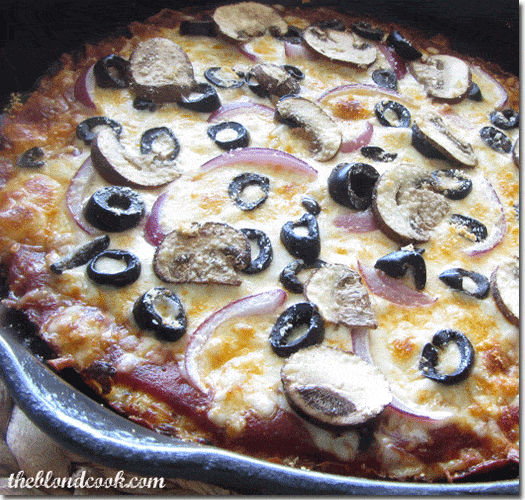 A closeup view of vegetable pizza in a cast iron skillet.