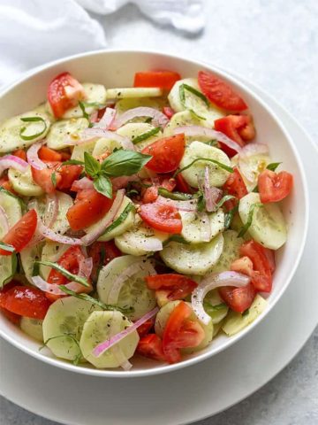 Overhead view of Cucumber tomato salad in a round white serving bowl