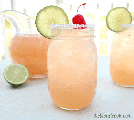 Front view of a margarita in a mason jar garnished with a lime wheel and cherry.