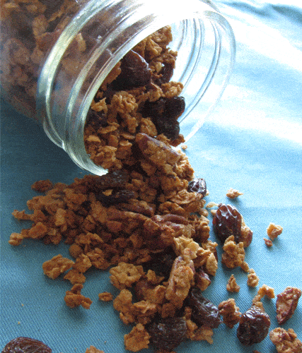 A glass jar on its side with granola coming out of the jar on a blue cloth napkin.