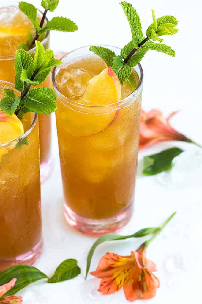 Three glasses of iced spiked peach tea with whiskey.