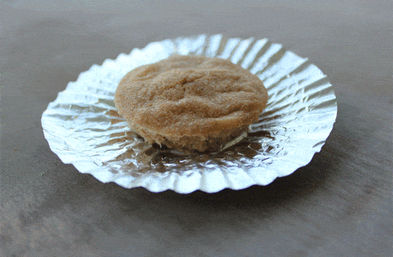 A baked dog treat in a silver cupcake liner that has been opened. 