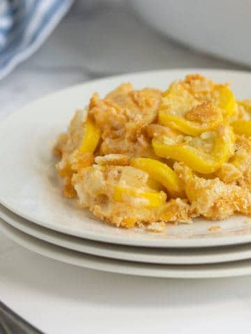 Front view of cheesy squash casserole on a white plate beside a fork.