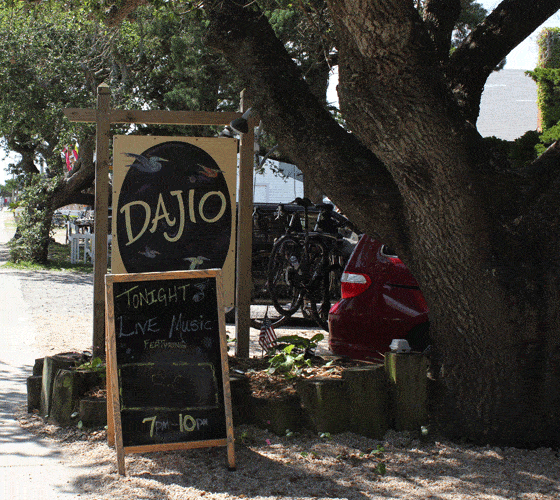 A sign that reads 'Dajio' by a large tree outside.