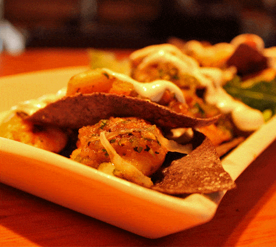 A closeup view of nachos topped with shrimp on a white plate.