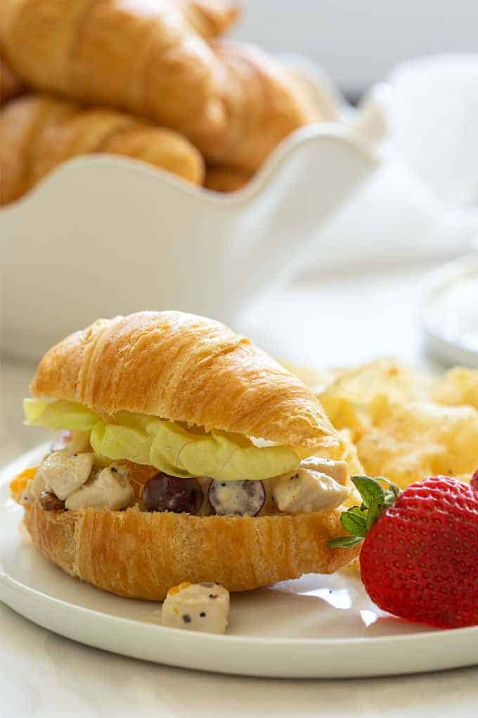 Chicken salad with oranges, pineapple and grapes on a white plate with fresh strawberries and potato chips