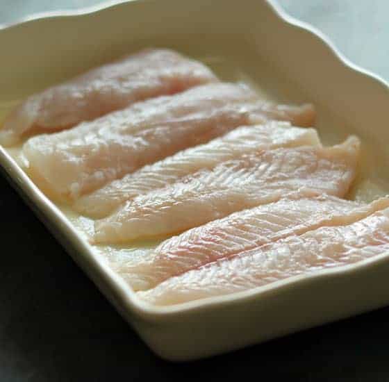 Raw fish filets in a white rectangle baking dish