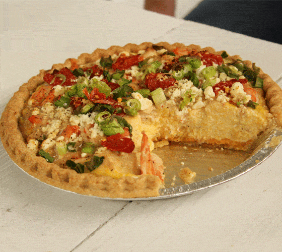 A shrimp and grits pie in a pie tin on a white wooden table.