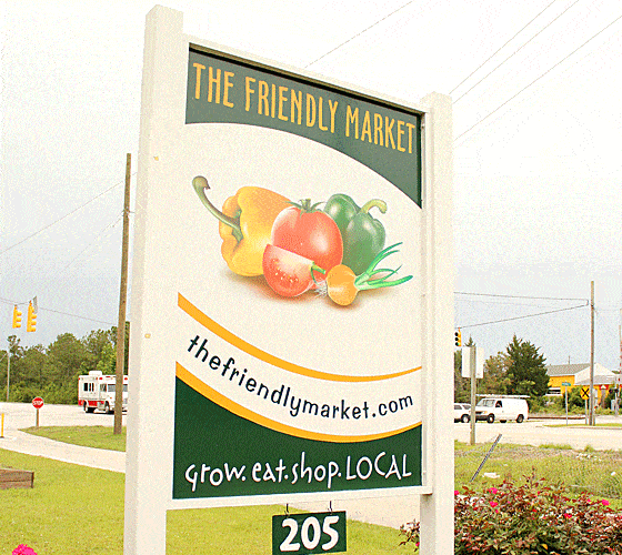 A large white outdoor sign with images of fresh vegetables in the center.