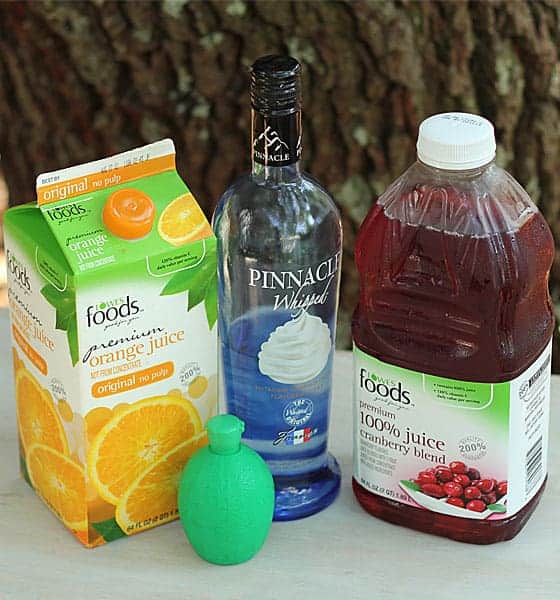 A container of orange juice, bottles of vodka and cranberry juice and container of lime juice.
