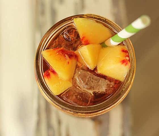 Overhead view of a whiskey cocktail with fresh chopped peaches.