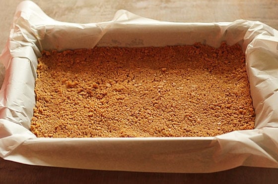 Graham cracker crust in a rectangle baking pan lined with parchment paper.