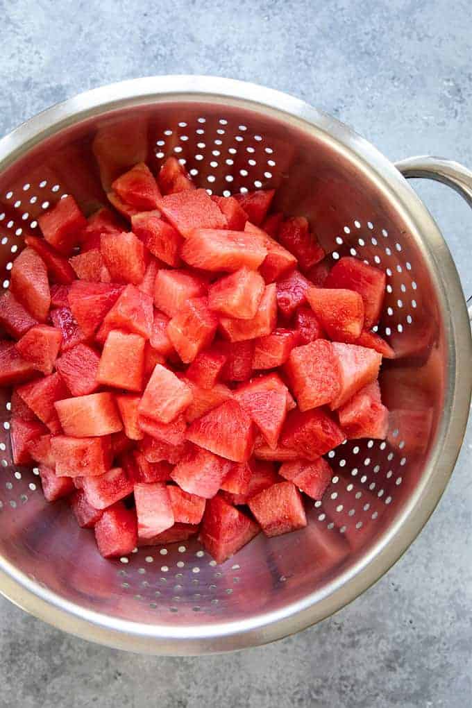 Cubed watermelon in a stainless colander.