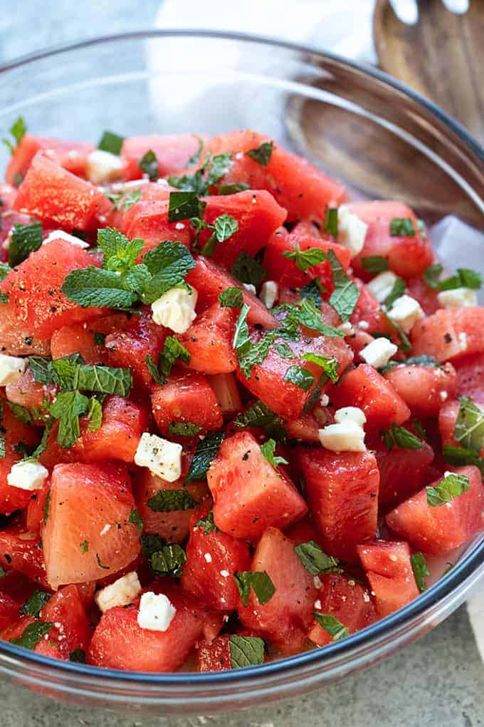 Closeup of watermelon salad in a clear glass bowl.