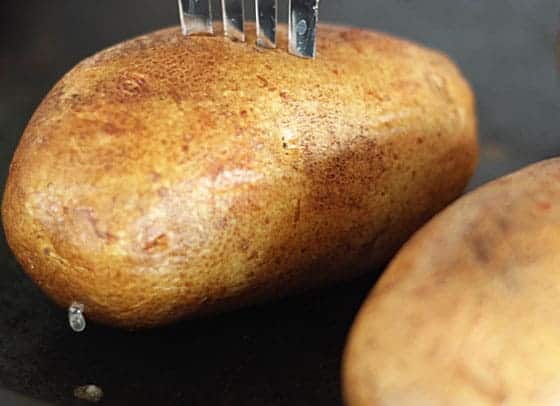 A fork piercing a baked potato.
