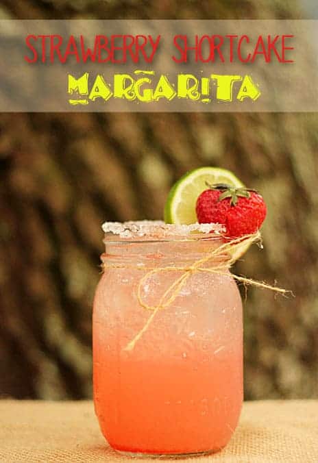 A pink margarita in a mason jar garnished with a strawberry and lime wheel. Text at top of image.