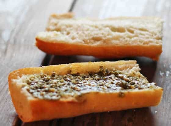 A 6 inch sliced baguette that has been spread with pesto.