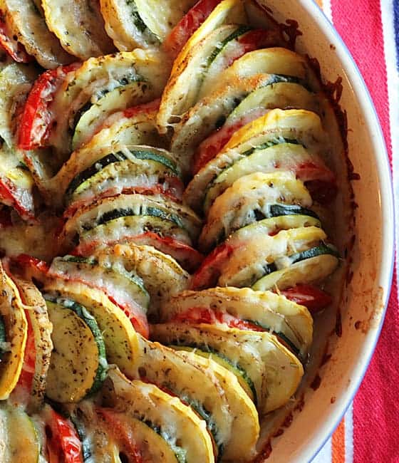 Overhead closeup view of baked vegetable tian in a round baking dish.