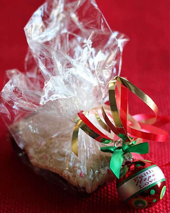 A brownie wrapped in plastic wrap and tied with holiday ribbon and an ornament.