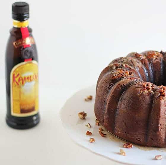 Partial view of a chocolate bundt cake with a bottle of liqueur on the left.