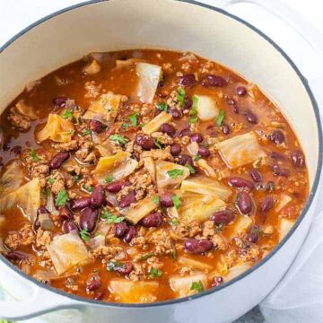 Soup with ground turkey, kidney beans and cabbage in a white dutch oven.