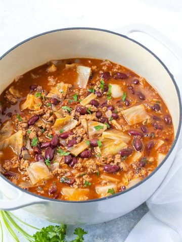 Soup with ground turkey, kidney beans and cabbage in a white dutch oven.