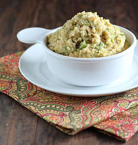 Broccoli and cheese quinoa in a white bowl on a white plate on a patterned napkin.  