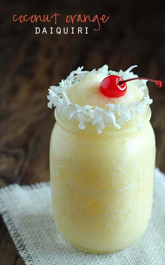 A daiquiri topped with a cherry in a mason jar rimmed with coconut. Text at top of image.