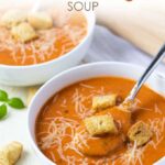 A closeup of a spoonful of tomato soup in a white bowl.  Overlay text at top of image.