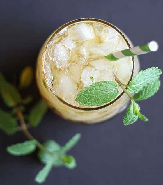 Overhead view of a mint julep cocktail on a black surface.