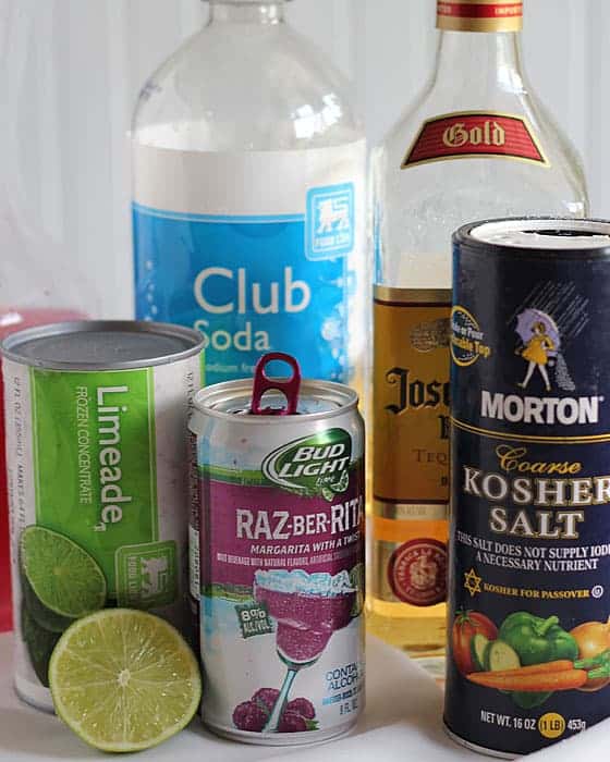 A can of limeade concentrate, club soda, tequila, kosher salt, a can of raspberry beer and a lime.