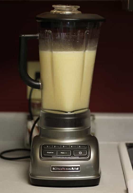 A blender filled with frozen pineapple coconut margarita sitting on a counter.