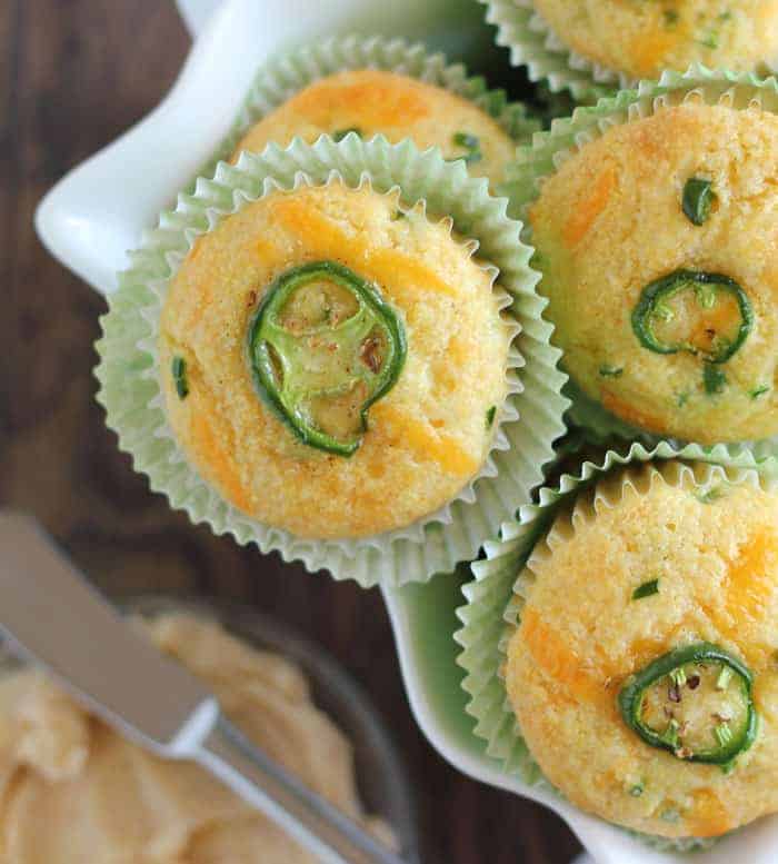 Closeup overhead view of cheddar corn muffins with a sliced jalapeno baked in the top.