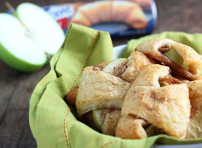 A bowl of apple pie bites. A tube of crescent rolls is in the background.