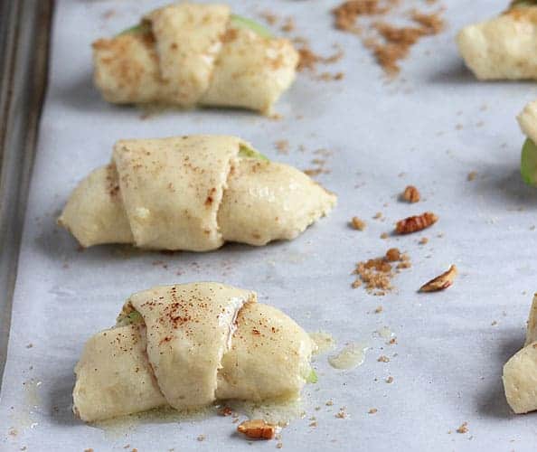 Unbaked apple pie bites on a baking sheet lined with parchment paper.