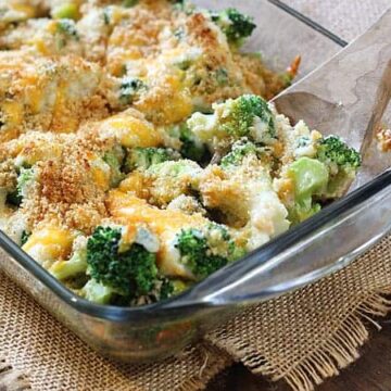 Broccoli au gratin in a glass baking dish with a wooden spoon.