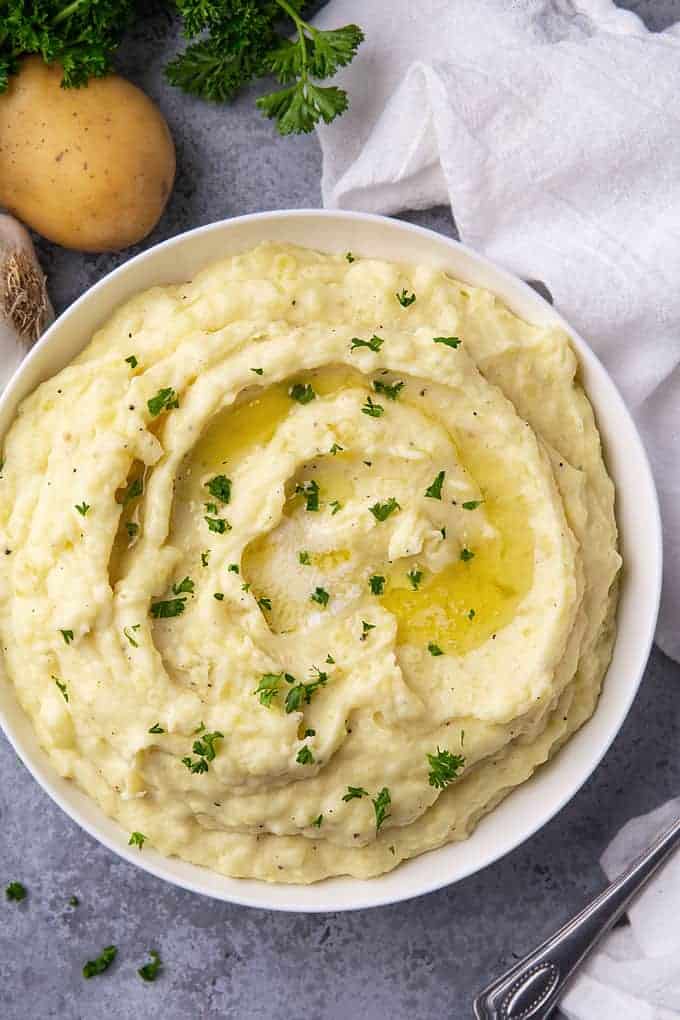 Mashed potatoes garnished with fresh parsley in a round white bowl