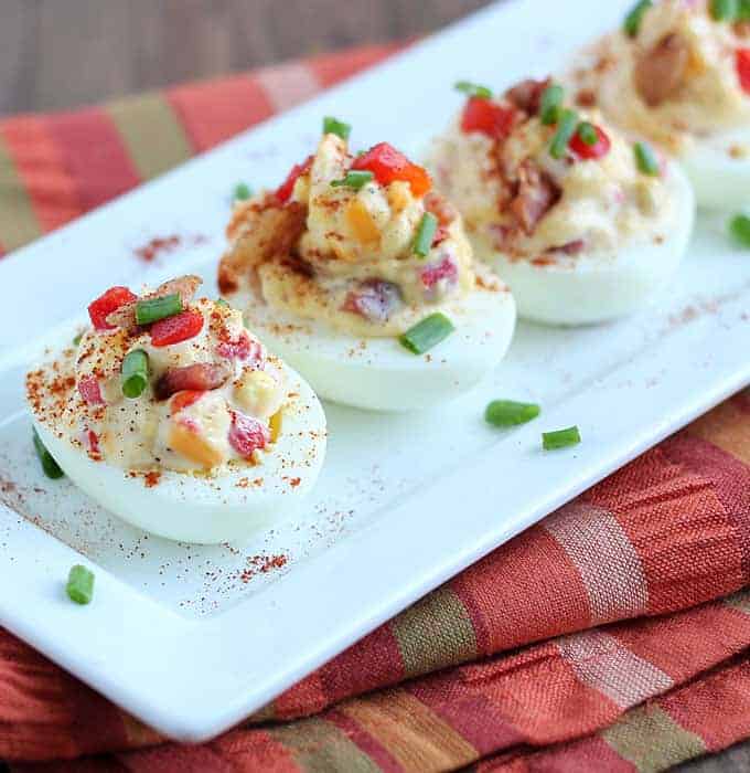 Closeup view of deviled eggs topped with fresh chives and paprika.