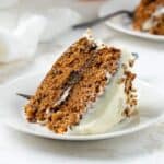 A slice of carrot cake on a white plate with a fork.