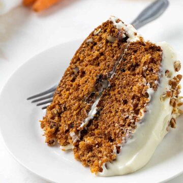 A slice of carrot cake on a white plate with a fork.