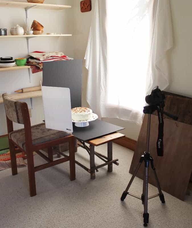 Behind the scenes of photographing cake.  A cake is on top of a black piece of foam board and a foam board is propped up behind cake.