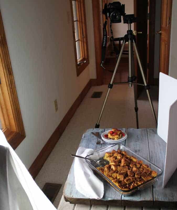 Behind the scenes of photographing a casserole.  Food is on a wooden background beside a window.  